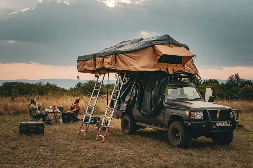 A couple camping in Masai Mara during a self drive safari with a land cruiser in a rooftop tent